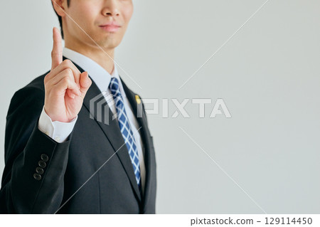 A young lawyer posing with his index finger raised A young lawyer posing with his index finger raised 129114450