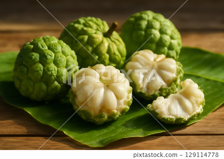 AI generated close-up of fresh sugar apple fruits on banana leaves, with peeled fruit revealing juicy flesh. Vibrant sunlight and water droplets on the fruits create a natural tropical atmosphere 129114778