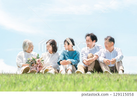 一個可以看到藍天的公園,一個坐在山上的家庭,父母和孩子,一個三代家庭(父親,母親,女兒,祖母,祖父) 一個可以看到藍天的公園,一個坐在山上的家庭,父母和孩子,一個三代家庭(父親,母親,女兒,祖母,祖父) 129115058