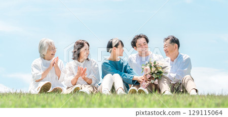 一個可以看到藍天的公園，一個坐在山上的家庭，父母和孩子，一個三代家庭（父親，母親，女兒，祖母，祖父） 129115064