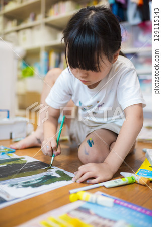 一個孩子坐在地板上認真畫畫 一個孩子坐在地板上認真畫畫 129115143