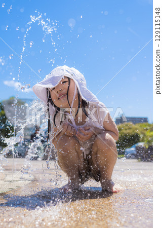 Children enjoying splashing around in a fountain in the summer sunshine 129115148