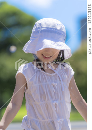 A girl playing in the fountain plaza while splashing with water 129115158