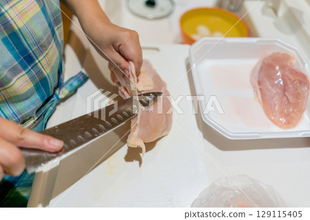 Housewife cutting chicken breast Housewife cutting chicken breast 129115405