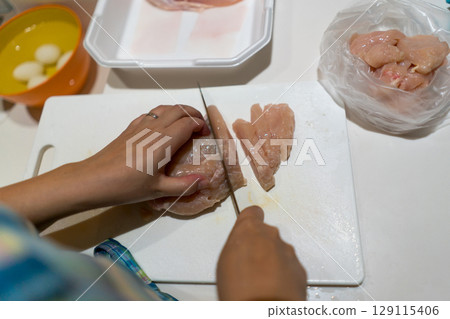 Housewife cutting chicken breast 129115406
