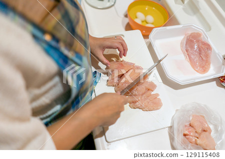 Housewife cutting chicken breast 129115408