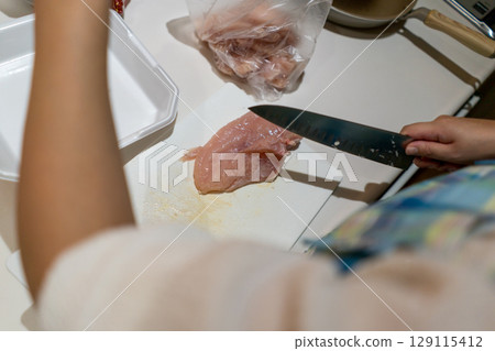 Housewife cutting chicken breast Housewife cutting chicken breast 129115412