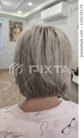 Woman with long light dyed hair standing in beauty salon with back. Ash shade. 129116174