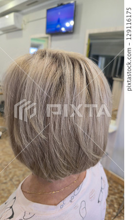 Woman with long light dyed hair standing in beauty salon with back. Ash shade. 129116175