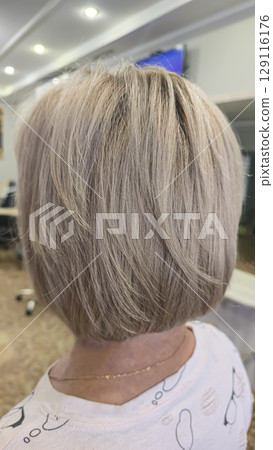 Woman with long light dyed hair standing in beauty salon with back. Ash shade. 129116176