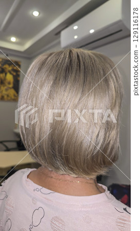 Woman with long light dyed hair standing in beauty salon with back. Ash shade. 129116178
