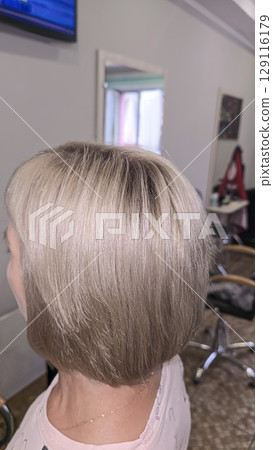 Woman with long light dyed hair standing in beauty salon with back. Ash shade. 129116179