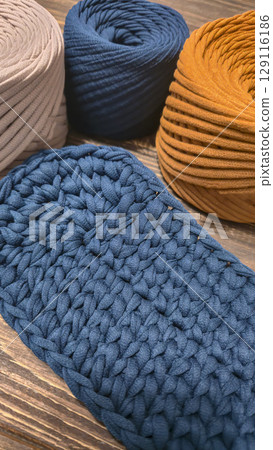 The bottom of the bag is crocheted from blue knitted yarn On a wooden background 129116186