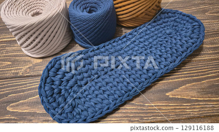 The bottom of the bag is crocheted from blue knitted yarn On a wooden background 129116188