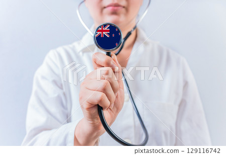 Female doctor holding stethoscope with New Zealand flag. National health system of New Zealand 129116742