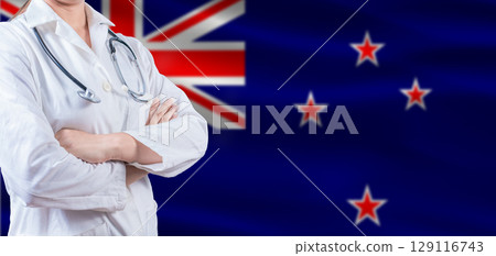 Doctor with crossed arms on New Zealand flag. New Zealand health and care concept. Female doctor on New Zealand flag 129116743