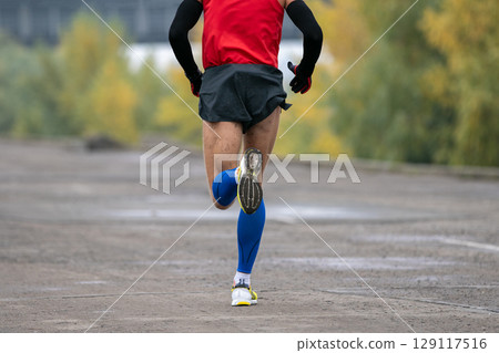 back view man running marathon in long sleeve and compression socks back view man running marathon in long sleeve and compression socks 129117516
