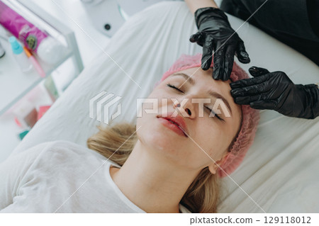 young woman getting professional face massage at aesthetic clinic 129118012