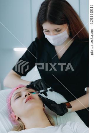 an aesthetic professional performing a rejuvenation injection procedure. Beauty treatment 129118015