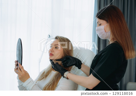 woman looking in a mirror after facian rejuvenation procedure at aesthetic clinic woman looking in a mirror after facian rejuvenation procedure at aesthetic clinic 129118016