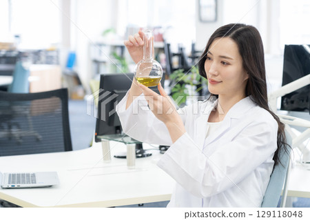 一位身穿白大褂的年輕女研究員在實驗室進行實驗 129118048