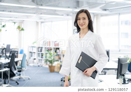 A young female researcher in a white coat conducting an experiment in a laboratory A young female researcher in a white coat conducting an experiment in a laboratory 129118057
