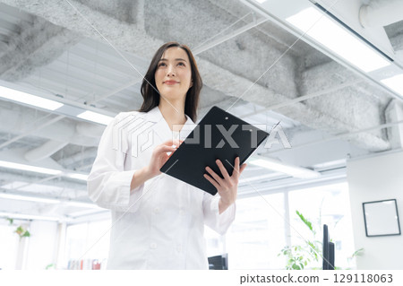 A young female researcher in a white coat conducting an experiment in a laboratory A young female researcher in a white coat conducting an experiment in a laboratory 129118063
