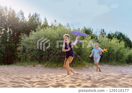 cute caucasian boys running along beach holding toy planes cute caucasian boys running along beach holding toy planes 129118177
