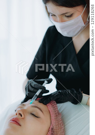 aesthetic professional performing an injection procedure in the glabellar region. Beauty treatment 129118268