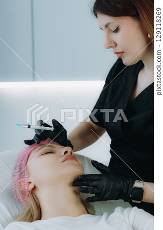 an aesthetic professional performing an injection procedure. Beauty treatment 129118269