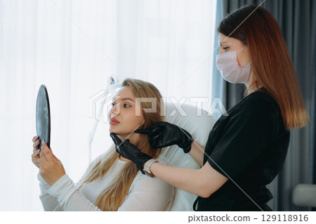 woman looking in a mirror after facian rejuvenation procedure at aesthetic clinic woman looking in a mirror after facian rejuvenation procedure at aesthetic clinic 129118916