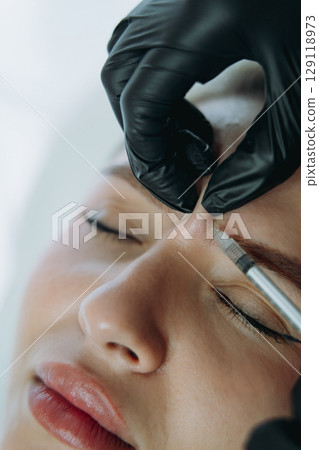 close up of professional hands making Botox ingection into woman frown line close up of professional hands making Botox ingection into woman frown line 129118973