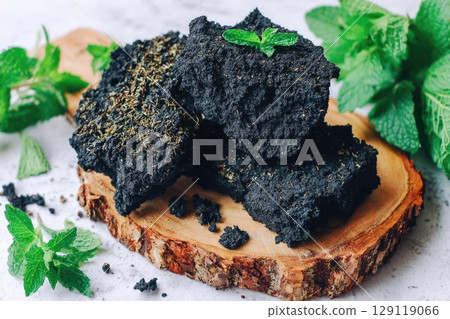 shilajit rock placed on a rough-cut wooden board with visible grain. 129119066
