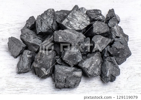 Dark sticky shilajit chunks placed on a whitewashed wooden board. Top view 129119079