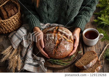 woman hands holding a freshly baked sourdough bread 129119268