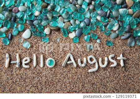 turquoise stones and pebbles text Hello august on sand 129119371
