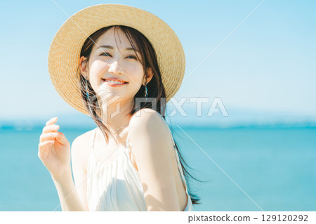 戴著草帽的女人，背景是海和藍天 129120292