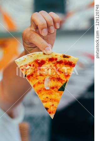 Hand Holding Slice of Hot Ham and Cheese Pizza 129120748