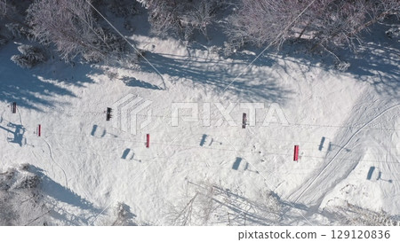 Aerial drone of ski lift, snowy mountain slope, surrounded by snow covered trees, on a sunny winter day, tranquil and picturesque view. Bukovel ski resort. Winter wild nature travel background 129120836