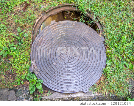 A slightly open sewer hatch. Concept of danger in the city. Unfinished work. 129121054