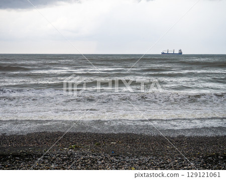 lonely ship in the middle of a rough sea. Barge in the distance. Big waves on the sea. After the storm. Bad weather.  Ship on the horizon 129121061