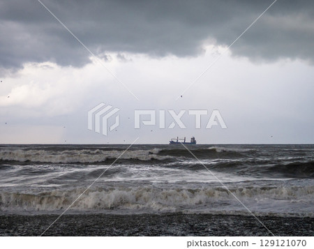lonely ship in the middle of a rough sea. Barge in the distance. Big waves on the sea. After the storm. Bad weather. Ship on the horizon lonely ship in the middle of a rough sea. Barge in the distance. Big waves on the sea. After the storm. Bad weather. Ship on the horizon 129121070