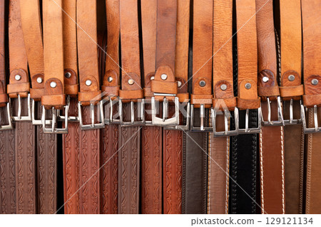 Selection of brown leather belts offered at a market stall 129121134