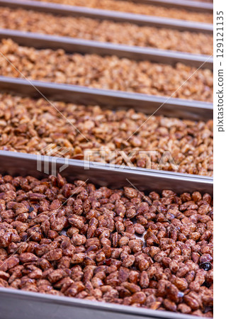 Selection of roasted nuts offered at a market stall Selection of roasted nuts offered at a market stall 129121135