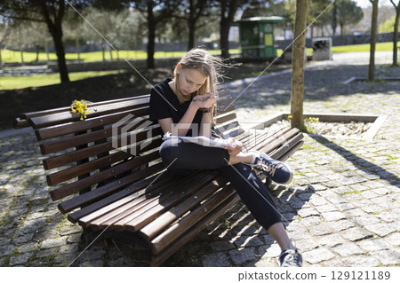 Young student girl studying outdoors on park bench Young student girl studying outdoors on park bench 129121189