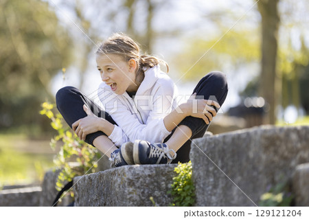 Young girl showing enthusiasm while sitting in a park Young girl showing enthusiasm while sitting in a park 129121204