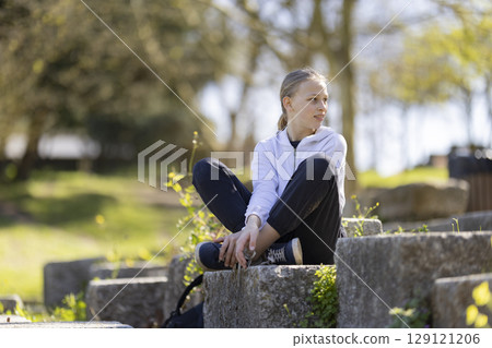 Girl sitting in a park enjoying the sunny day 129121206