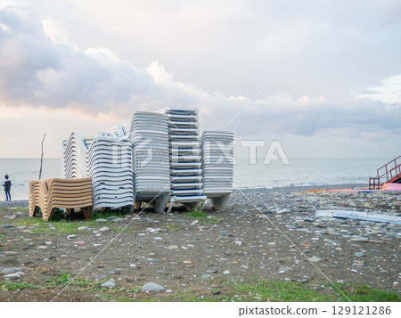 Folded sun loungers. End of season  at the resort concept . The rest is over. Sunbeds stacked on top of each other. Business on the seashore. Services for a comfortable holiday on the beach. 129121286