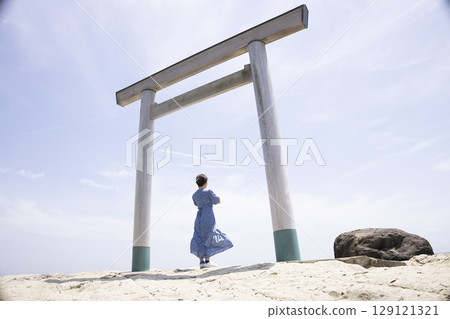一位女士站在海岸邊的鳥居門前 129121321
