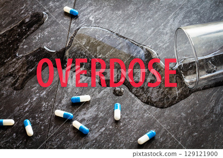 The inscription overdose on the background of scattered pills and spilled water. 129121900